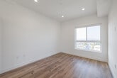 Located at 5801 W Pico Blvd, Unit 511 in Los Angeles, this modern residential unit offers a thoughtfully designed single-floor layout with clean lines and contemporary finishes. Warm hardwood-style flooring flows seamlessly throughout the living areas and bedroom, creating a cohesive and inviting atmosphere. The open-concept living area is bathed in natural light, anchored by a sliding glass door that opens directly onto a private balcony with open views of the surrounding Los Angeles cityscape and treetops. The kitchen is well-appointed with sleek taupe cabinetry, white countertops, a textured tile backsplash, and a full suite of stainless steel appliances including a gas range, microwave, dishwasher, and a large side-by-side refrigerator. In-unit laundry is also conveniently accessible. The bedroom is generously sized, featuring its own sliding glass door to the balcony, a built-in closet with integrated shelving and drawers, and an abundance of natural light. The bathroom is finished with large-format neutral floor tiles and features a tub-shower combination with sliding glass doors and textured tile surround. Recessed lighting throughout adds a polished, modern feel to every room.