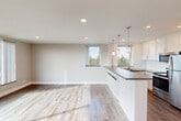 Located at 120 W Third Ave in San Mateo, California, this thoughtfully designed one-bedroom, one-bathroom residence offers a clean, contemporary aesthetic throughout its well-appointed single floor. Light-toned hardwood-style flooring runs continuously through the space, complementing the neutral palette of soft whites and warm grays.

The open-concept kitchen and living area forms the heart of the home. The kitchen is equipped with stainless steel appliances—including a refrigerator, range, dishwasher, and built-in microwave—paired with crisp white cabinetry, sleek dark countertops, and a white subway tile backsplash. A peninsula with pendant lighting above separates the kitchen from the living area, which benefits from abundant natural light streaming through multiple windows with treetop views.

The spacious bedroom features a large picture window framing sweeping hillside and neighborhood views, recessed lighting, crown molding, and two closets providing generous storage. The bathroom is finished with white subway tile wainscoting, brushed nickel fixtures, and a wall-mounted cabinet for additional storage.

Throughout the residence, recessed lighting, clean white trim, and carefully considered finishes create a bright, modern, and cohesive living environment.