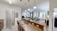 Located at 2670 Dry Pocket Rd in Greer, SC, this single-floor residence offers a thoughtfully designed open-concept layout across two bedrooms, two bathrooms, and multiple living spaces. The interior is finished with light neutral tones throughout, with tile flooring in the wet areas and plush carpet in the living and bedroom spaces.

The kitchen serves as a central hub, featuring warm wood cabinetry, granite-style countertops, a peninsula with a double stainless steel sink, pendant lighting above, and black appliances including a range, microwave, and refrigerator. The peninsula opens directly to the combined dining and living area, making the space ideal for entertaining.

The living room is generously proportioned, adorned with crown molding, a ceiling fan, and recessed lighting. Architectural columns define a sunlit sitting nook framed by multiple windows that bring in abundant natural light. An adjacent dining area flows seamlessly from the living room.

The primary bedroom is a comfortable retreat with vaulted ceilings, a walk-in closet equipped with wire shelving, and direct access to its own bathroom. The bathrooms feature tub-shower combinations with tile surrounds and vanities with warm wood cabinetry. A dedicated laundry room with washer/dryer connections and built-in wire shelving adds everyday convenience. Four total closets ensure ample storage throughout.