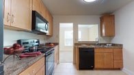 This two-floor home offers a practical and comfortable layout with consistent finishes throughout. The kitchen is well-appointed with light maple cabinetry, dark granite-style countertops, and a full suite of black appliances including a refrigerator, electric range, over-the-range microwave, and dishwasher. Light tile flooring runs throughout the kitchen, which also features a pass-through window connecting to an adjacent area, enhancing the open feel of the space.

The main living area on the first floor is carpeted and brightened by natural light through multiple windows with blinds. A staircase leads to the upper level, where additional carpeted bedrooms are found. One upper bedroom features vaulted ceilings and a large window with outdoor views, lending a bright and airy character to the space. Other bedrooms on this level are well-sized with generous windows that bring in ample natural light and views of surrounding greenery.

The home includes two full bathrooms, each featuring a soaking tub and shower combination with beige tile surrounds and chrome fixtures, providing a clean and neutral aesthetic. Neutral wall tones, wall-to-wall carpeting in the living and bedroom areas, and consistent trim work throughout create a cohesive and move-in ready environment across both floors.