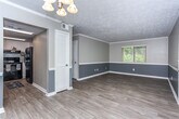 Located at 4570 St Marys Rd in Columbus, Georgia, this single-story home offers a well-designed layout with thoughtfully updated interiors throughout. The open living and dining area is finished with light wood-look flooring and a two-tone gray wall treatment accented by crisp white crown molding and baseboards, creating a clean, modern aesthetic. A chandelier anchors the dining space, adding a touch of elegance to the room.

The kitchen is a standout feature, showcasing white shaker-style cabinetry, granite countertops with subtle gray and white veining, a stainless steel sink, and a granite backsplash. A black electric range serves as a practical centerpiece, and ample cabinetry provides generous storage space.

The bedrooms offer a comfortable retreat, with plush carpeting, neutral gray walls, and ceiling fan fixtures that enhance both comfort and functionality. Natural light filters in through windows fitted with blinds.

The bathroom reflects the same attention to detail found throughout the home, featuring a vanity topped with matching granite countertops, white cabinetry with brushed nickel hardware, wood-look flooring, and a tub-shower combination. The overall ambiance of the home is cohesive and move-in ready, blending practical design with modern finishes.
