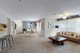 This single-floor residence offers a thoughtfully designed open layout that seamlessly connects the living, dining, and entry areas, all finished with plush wall-to-wall carpeting. The living room serves as the centerpiece of the home, highlighted by a white tile-surround fireplace, a ceiling fan, and a bank of large windows that draw in generous natural light and frame views of the surrounding greenery. A dedicated dining area sits adjacent, providing an organized and functional space for everyday living.

The two bedrooms are generously proportioned, each featuring ceiling fans, carpeted floors, and striking deep-blue accent walls that lend a bold, contemporary feel. Both rooms are fitted with ample closet space and are brightened by natural light from large windows with curtains.

The bathrooms are clean and functional, offering wide vanity countertops with under-sink cabinetry, large mirrors, and wood-look flooring. A utility area houses the in-unit washer and dryer alongside additional cabinetry and a full-size refrigerator, adding significant everyday convenience. Neutral gray walls throughout the common areas create a calm, cohesive palette, while accent walls and decor details add personality. The overall ambiance is comfortable, modern, and move-in ready.