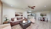Located at 2247 Wellspring Dr in Beaumont, Texas, this single-story home offers a thoughtfully designed layout across a comfortable footprint. The entryway welcomes visitors with light-toned tile flooring and a clean, neutral palette that carries throughout the main living areas. The open-concept kitchen is a functional highlight, featuring white cabinetry, stainless steel appliances, a large peninsula with a gray countertop and bar seating, and recessed lighting — ideal for both everyday cooking and casual dining. An adjacent dining area provides additional space for meals and entertaining. The bedrooms are carpeted and each equipped with ceiling fans for year-round comfort. Natural light filters in through windows dressed with panel curtains, lending a warm atmosphere to the sleeping quarters. The bathrooms feature wood-look tile flooring, with one bathroom offering a full shower-tub combination and direct access to a walk-in closet with built-in shelving and hanging rods. A dedicated laundry room houses a full-size washer and dryer alongside upper cabinetry for storage, with the electrical panel conveniently located within the same space. Outside, a fenced backyard with a grassy lawn offers an open, airy outdoor area with views of the surrounding landscape under wide Texas skies.