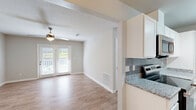 This well-appointed 1-bedroom, 1-bathroom unit in LaGrange, Georgia offers a thoughtfully designed single-level layout that maximizes functionality and comfort. The living room is bright and welcoming, featuring light wood-style flooring, neutral walls, a ceiling fan with light fixture, and French doors that open to an outdoor patio, allowing natural light to fill the space. Adjacent to the living area, the dining room provides a seamless transition into the kitchen, which is a standout feature of the home. The kitchen is equipped with white shaker-style cabinetry, granite countertops, a stainless steel double-basin sink, a stylish gray subway tile backsplash, and stainless steel appliances, including a refrigerator, range, and dishwasher. A pendant light over the dining area adds a refined touch. The bedroom is a comfortable retreat with plush carpeting, a ceiling fan, natural light from a window with blinds, and multiple closets for generous storage. The full bathroom continues the granite aesthetic with a dual-sink vanity, wood-look flooring, and a tub-shower combination. A utility room and additional hallway closets round out the practical features of this functional and attractive home.