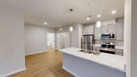 Located in Anderson, SC, this thoughtfully designed one-bedroom, one-bathroom residence offers a modern aesthetic combined with functional living. The open-concept kitchen and living area serves as the heart of the home, anchored by a central island with a sleek marble-look countertop, undermount sink, and pendant lighting above. The kitchen is fully equipped with stainless steel appliances—including a refrigerator, electric range, microwave, and dishwasher—complemented by gray shaker-style cabinetry and ample counter space. Warm-toned luxury vinyl plank flooring flows seamlessly throughout the entire unit, creating a cohesive and easy-to-maintain surface underfoot. The living area is bright and open, with natural light filtering in and a ceiling fan overhead. The spacious primary bedroom offers a comfortable retreat with a ceiling fan, a large window with outdoor views, and direct access to a dedicated walk-in closet equipped with wire shelving. The walk-in closet also conveniently houses the laundry connections. The bathroom features coordinating gray cabinetry and clean, contemporary finishes. Neutral wall tones throughout the home provide a versatile backdrop, completing this modern and move-in-ready residence.