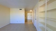 This two-story residence offers a straightforward and functional layout designed for comfortable everyday living. The interior presents a clean, neutral palette throughout, with light-toned walls that create a bright and open atmosphere. Tile flooring runs through the main living areas, offering both durability and ease of maintenance.

A standout feature of the main level is the built-in shelving unit, which provides generous storage and display space along one wall — a practical addition that adds character to the room. The open hallway connects the living areas and leads toward a glass door at the rear, which allows natural light to filter through the space and hints at outdoor access beyond.

The textured ceilings and centrally positioned light fixtures contribute to the home's understated, no-frills aesthetic. HVAC vents are integrated into both the ceiling and lower wall areas, ensuring climate comfort throughout the space. A louvered closet door along the hallway offers additional enclosed storage conveniently positioned near the main living area.

Overall, the space communicates a clean, move-in-ready character with functional design choices, neutral finishes, and a layout that flows naturally between the main living zone and the rest of the home across both floors.