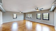 Located at 2647 Erie Ave in Cincinnati's 45208 zip code, this 2-bedroom, 1-bathroom single-floor residence combines classic character with modern updates. The expansive main living area immediately impresses with its stunning herringbone-patterned hardwood floors, neutral gray walls, and multiple black-framed grid windows that flood the space with natural light and offer views of the surrounding neighborhood. Dual ceiling fans ensure year-round comfort throughout the generously sized living space. Exposed silver ductwork lends an industrial touch as the living area transitions toward the bedrooms and kitchen. The kitchen is outfitted with white shaker cabinetry, light gray countertops, a stainless steel refrigerator, electric range with over-the-range microwave, and a dishwasher, complemented by a window above the sink. Each bedroom continues the herringbone hardwood flooring and ceiling fan combination, maintaining a consistent and cohesive aesthetic. The bathroom features a clean, bright design with white subway tile surrounding a tub-shower combo with sliding glass doors, a single vanity sink, and mirrored medicine cabinet. This well-appointed residence offers a timeless yet functional living environment in a desirable Cincinnati neighborhood.