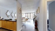 Located at 777 S State Street in Chicago's South Loop neighborhood, this single-floor residence offers a well-designed layout that balances open communal spaces with private retreats. Dark hardwood floors flow throughout, providing a warm contrast to the crisp white walls and textured ceilings found across the unit.

The entryway opens into a long, light-filled corridor that leads to the main living area. Floor-to-ceiling windows dominate the living room, framing elevated views of the surrounding Chicago skyline and flooding the space with natural light. The living area transitions seamlessly into a dining space and kitchen, creating an open, connected feel ideal for everyday living and entertaining.

The kitchen features light maple cabinetry, dark granite-toned countertops, and black appliances, including a refrigerator and electric range. A hallway off the kitchen leads to the bedroom and bathroom. The bedroom offers ample closet space, hardwood floors, and large windows that continue the unit's theme of natural light and urban views. The bathroom includes a tiled tub-shower combination and built-in cabinetry for storage.

Throughout, the space maintains a modern, functional character with clean lines and a neutral palette well-suited to city living.