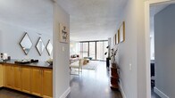 Located at 777 S State Street in Chicago's South Loop neighborhood, this single-floor residence offers a well-designed layout that balances open communal spaces with private retreats. Dark hardwood floors flow throughout, providing a warm contrast to the crisp white walls and textured ceilings found across the unit.

The entryway opens into a long, light-filled corridor that leads to the main living area. Floor-to-ceiling windows dominate the living room, framing elevated views of the surrounding Chicago skyline and flooding the space with natural light. The living area transitions seamlessly into a dining space and kitchen, creating an open, connected feel ideal for everyday living and entertaining.

The kitchen features light maple cabinetry, dark granite-toned countertops, and black appliances, including a refrigerator and electric range. A hallway off the kitchen leads to the bedroom and bathroom. The bedroom offers ample closet space, hardwood floors, and large windows that continue the unit's theme of natural light and urban views. The bathroom includes a tiled tub-shower combination and built-in cabinetry for storage.

Throughout, the space maintains a modern, functional character with clean lines and a neutral palette well-suited to city living.