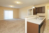 This single-floor unit offers a thoughtfully designed layout that balances functionality and comfort throughout its various spaces. The kitchen is a standout feature, equipped with rich dark espresso cabinetry that extends to the ceiling, light-toned countertops, tile flooring in a stone-like pattern, and a full suite of black appliances including a refrigerator with ice maker, electric range, and microwave. A breakfast bar provides additional counter space and a casual dining option, while a pendant light adds a warm accent overhead. In-unit laundry connections are conveniently located just off the kitchen.

The living area is generously sized, featuring plush wall-to-wall carpeting, neutral warm-toned walls, and a sliding glass door with vertical blinds that brings in natural light. The open sightlines between the living area and kitchen create a cohesive, connected feel. The bedrooms are carpeted and well-proportioned, each with windows that allow natural light to filter in. Two bathrooms serve the unit — one featuring a tub-shower combo with a single vanity and tile flooring, and the other offering a walk-in glass-enclosed shower, matching dark cabinetry, and a well-lit vanity with a large mirror. Clean white trim and textured ceilings are consistent throughout the space.