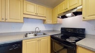 Located at 1025 S Beach St in Daytona Beach, Florida, this single-floor residence offers a practical and comfortable layout designed for everyday living. The kitchen is well-appointed with warm yellow cabinetry providing ample upper and lower storage, speckled laminate countertops, a double stainless steel sink, tile flooring, and a black electric range with an overhead ventilation hood — offering a fully functional cooking environment. The living area features a combination of hard flooring and plush wall-to-wall carpeting, with large vertical-blind-covered sliding doors that invite natural light and offer outdoor views, creating a bright and open atmosphere. The bedrooms are carpeted for comfort and each include ceiling fans with light fixtures and windows dressed with vertical blinds that allow filtered natural light to illuminate the rooms. One bedroom features a built-in closet, adding practical storage. The bathroom is clean and efficient, featuring warm-toned floor tiles, a vanity with wood-finish cabinetry, a white toilet, and a full tub-shower combination enclosed with white subway-style tiles and accented with brushed gold hardware. Overall, the space presents a neutral, move-in-ready interior in a convenient Daytona Beach location.