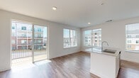 Located at 2950 Richmond Row Drive in Suwanee, GA, this single-floor residence offers a clean, modern aesthetic throughout. The open-concept living and dining area is bright and welcoming, with large windows and a sliding glass door that floods the space with natural light and provides direct access to a private balcony finished with wood decking and black metal railings. The exterior brick facade adds a classic architectural contrast to the contemporary interior finishes.

The kitchen is a standout feature, boasting a large granite-topped island with an undermount sink, white shaker-style cabinetry, subway tile backsplash, and a full suite of stainless steel appliances, including a refrigerator, range, and built-in microwave. Hardwood-style plank flooring runs throughout the main living areas, lending warmth and continuity to the space.

The bedrooms are carpeted for comfort, each offering generous closet space and ceiling fans or dedicated lighting. The bathrooms are well-appointed with granite vanity countertops, white cabinetry, and hardwood-style flooring. A hallway connects the private areas of the residence, maintaining a logical and functional flow throughout. The overall ambiance is bright, neutral, and move-in ready.