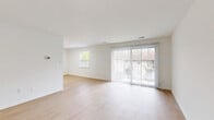 This two-bedroom, one-bathroom residence in Owings Mills, Maryland offers a thoughtfully designed single-floor layout with a clean, modern aesthetic throughout. The open-concept living and dining area is bright and airy, featuring light-toned luxury vinyl plank flooring and large sliding glass doors dressed with vertical blinds that invite natural light and provide access to an outdoor area. A secondary window further enhances the sense of openness in the living space.

The kitchen is well-appointed with crisp white shaker-style cabinetry, sleek stone countertops, and a full suite of stainless steel appliances including a gas range, dishwasher, and refrigerator. A peninsula counter adds additional prep and serving space, making the kitchen both functional and visually appealing.

Both bedrooms are carpeted in a warm neutral tone, offering a comfortable and quiet retreat. The primary bedroom features a set of full-length closet doors providing generous storage, while the second bedroom includes a window with garden views and natural light. The bathroom is clean and classic, featuring white subway tile surrounding a full soaking tub and shower combination with chrome fixtures. A hallway and entrance area complete the efficient, well-organized floor plan.