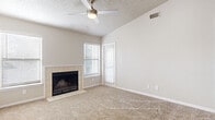 Located in the established Gulf Gate Estates community of Sarasota, Florida, this single-story home offers a comfortable and functional layout with thoughtful interior details throughout. The spacious living area serves as the heart of the home, highlighted by vaulted ceilings, a ceiling fan with light fixture, and a textured ceiling finish. A tile-surround wood-burning fireplace anchors the room, while large windows fitted with blinds allow natural light to fill the carpeted space. The open sightlines and generous proportions create an airy, welcoming atmosphere. The kitchen is outfitted with white shaker-style cabinetry, light countertops, wood-look vinyl plank flooring, and black appliances including a refrigerator and range, offering both style and practicality. The bathroom features a clean, updated design with a white vanity, light stone-style countertop, framed mirror, tub-shower combination, and rich dark wood-look flooring that adds contrast to the bright white fixtures. The bedroom is generously sized with plush carpeting, a ceiling fan, and direct access to an adjacent laundry area. Additional rooms provide flexible space with neutral finishes, carpet flooring, and ample natural light, completing this well-maintained Florida home.