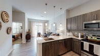 Located at Market Point Drive in Greenville, SC, this single-floor residence showcases a contemporary design with high-end finishes throughout. The open-concept kitchen is a standout feature, equipped with stainless steel appliances, rich dark wood cabinetry extending to the ceiling, and a generous granite-topped island with pendant lighting — ideal for both meal prep and casual dining. Light wood-style flooring flows seamlessly through the main living areas, lending a warm, cohesive feel.

The living area benefits from large floor-to-ceiling glass doors that invite abundant natural light and provide direct outdoor access, creating an airy, connected atmosphere. The bedroom is a comfortable retreat, featuring plush carpeting, ample natural light from well-placed windows, and generous closet access.

The bathroom is thoughtfully designed with a wide granite vanity, dark wood cabinetry, a large mirror, and a glass-enclosed walk-in shower with detailed tile work. Light tile flooring completes the clean, spa-like aesthetic.

Overall, the residence balances modern functionality with refined style, offering a cohesive and comfortable living environment well-suited to daily life in Greenville's vibrant Market Point community.