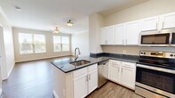 Located at 2701 Neabsco Common Pl, Unit 342 in Woodbridge, Virginia, this single-floor, 3-bedroom, 2-bathroom residence offers a thoughtfully designed layout that balances comfort and functionality. The open-concept kitchen and living area serves as the heart of the home, featuring wood-style plank flooring that flows throughout. The kitchen is outfitted with white shaker cabinetry, dark countertops, stainless steel appliances including a range, microwave, and refrigerator, and a peninsula island with a built-in sink — ideal for both cooking and casual dining. The adjoining living room benefits from natural light through large windows and is finished with crown molding and a ceiling fan. The primary bedroom is a generous, well-lit retreat with hardwood-style flooring, multiple windows with outdoor views, ceiling fan, and access to a walk-in closet with wire shelving. The secondary bedrooms feature soft carpeting, ceiling fans, and windows that invite natural light. Both bathrooms are finished with warm tile flooring and include a full tub-shower combination. A dedicated walk-in closet with wrap-around wire shelving adds practical storage to the primary suite.