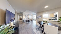This well-designed 3-bedroom, 2-bathroom single-floor residence in Las Vegas offers a thoughtful layout that maximizes comfort and functionality. The open-concept living, dining, and kitchen area forms the heart of the home, featuring wood-style flooring, neutral tones, and a ceiling fan that enhances the airy ambiance. Large windows allow natural light to fill the space, creating a bright and welcoming atmosphere. The living room provides ample room for seating, complemented by a large statement artwork on the wall. The dining area features an arched pass-through to the kitchen, adding architectural charm, while the kitchen is equipped with light wood cabinetry, white countertops, and black appliances including a gas range and over-the-range microwave. The primary bedroom offers vaulted ceilings and plush carpeting, with access to dedicated closet space. A second bedroom features an accent wall in a calming blue-gray hue and a window with outdoor views. Both bathrooms include light wood vanities with dual sinks and ample mirror space. Two closets provide generous storage throughout. The overall design balances practicality with a clean, contemporary aesthetic suited for comfortable everyday living.