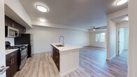 Located on Diamond Bar Place in Stockton, CA, this single-floor residence offers a clean, contemporary design throughout. The open-concept layout seamlessly connects the kitchen and living area, creating a bright and airy atmosphere enhanced by light-toned luxury vinyl plank flooring that runs consistently throughout the space.

The kitchen is a standout feature, anchored by a large center island with a white countertop and an integrated undermount sink fitted with a professional-style pull-down faucet. Rich dark-toned cabinetry lines the back wall, providing ample storage, while stainless steel appliances—including a gas range, built-in microwave, and refrigerator—complete the well-appointed cooking space. Flush-mount ceiling lights illuminate the area effectively.

The adjacent living area is generously proportioned, offering a relaxed, open feel. A ceiling fan with a light fixture and a window fitted with blinds allow for natural light and comfortable airflow.

The bedroom is bright and tranquil, with natural light filtering through window blinds and casting geometric patterns across the floor. A walk-in closet provides practical storage. The bathroom features a soaking tub with a tiled shower surround, warm gold-toned fixtures, a white vanity with countertop, and matching luxury vinyl plank flooring, maintaining a cohesive aesthetic throughout the home.