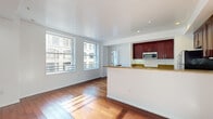 Located in the heart of Downtown Los Angeles, this 2-bedroom, 2-bathroom residence offers a well-designed single-level layout with a cohesive blend of modern finishes and urban character. Rich hardwood floors flow throughout the living areas and bedrooms, complementing the bright, white walls and clean architectural lines.

The open-concept living room is generously proportioned, bathed in natural light from large windows that frame views of Downtown LA's iconic historic buildings. It connects seamlessly to the kitchen, which is separated by a peninsula with granite countertops — ideal for casual dining or entertaining. The kitchen features rich dark-wood cabinetry, granite countertops, stainless steel appliances including a refrigerator, range, microwave, and dishwasher, and elegant tile flooring.

The primary bedroom is spacious and well-lit with multiple windows offering urban views and includes mirrored sliding closet doors. A dedicated walk-in closet with built-in shelving and a hanging rail provides ample storage. The second bedroom is bright and comfortable, also with city-facing windows. Both bathrooms are finished with dark wood vanities and matching granite countertops. The residence is further completed by two hallways that aid in a functional, organized flow throughout the home.