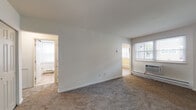 This one-bedroom unit at 2819 Kate Ave in Bensalem, PA offers a practical and comfortable single-floor layout. The living area is generously sized, featuring neutral wall-to-wall carpeting, crisp white walls, and a window-mounted air conditioning unit. Natural light filters in through multiple windows, creating a bright and welcoming atmosphere. Baseboard heating runs throughout the unit for efficient warmth. The bedroom provides a comfortable retreat with plush carpeting, a double-door closet offering ample storage, and a window that brings in additional natural light. The kitchen stands out with its rich, dark shaker-style cabinetry, light stone-look countertops, and a decorative mosaic tile backsplash. Wood-look flooring, black appliances including a range and dishwasher, and a stainless steel sink complete the functional and stylish space. The bathroom is clean and well-maintained, featuring tile flooring in warm neutral tones, a white vanity with brushed nickel hardware, a toilet, and a window with blinds providing natural light and privacy. The unit's straightforward layout and well-kept condition make it a practical living space in a residential Bensalem neighborhood.