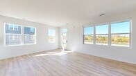 This well-designed single-story home offers a clean, modern aesthetic throughout its two bedrooms and two bathrooms. The open-concept living room serves as the heart of the home, featuring light hardwood flooring and an abundance of natural light streaming through multiple large windows that frame pleasant outdoor views of surrounding greenery. A glass-paneled front door further enhances the brightness of the living area.

The kitchen is well-appointed with white shaker-style cabinetry, quartz countertops, a central island, and stainless steel appliances, including a refrigerator, microwave, and range. Recessed lighting and light hardwood flooring complete the space.

A well-lit hallway with a sliding barn door connects the living areas to the private quarters. Both bedrooms feature plush carpeting and natural light from individual windows, offering a comfortable and quiet retreat. The primary bedroom provides a generous footprint with its own dedicated closet.

Both bathrooms maintain the home's clean, contemporary palette, featuring white shaker cabinetry, quartz countertops, chrome hardware, and large vanity mirrors. The primary bathroom includes a double-sink vanity. Light hardwood flooring ties each bathroom together seamlessly with the rest of the home's design.