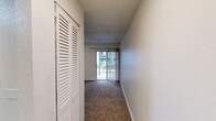Located at 3230 SW Archer Rd in Gainesville, Florida, this single-floor unit offers a practical and comfortable layout designed to make efficient use of its space. The kitchen is a standout feature, outfitted with bright white cabinetry extending to the ceiling, striking dark granite-style countertops, and a full suite of white appliances including a refrigerator, electric range, and dishwasher. Light tile flooring runs throughout the kitchen, lending a clean and airy feel to the space.

The generously sized primary bedroom is finished with plush carpeting and features dual louvered closet doors, offering ample storage. A ceiling fan overhead adds comfort, while the textured ceiling adds a classic touch consistent throughout the unit.

The living area continues the carpeted flooring and is highlighted by a wall of floor-to-ceiling sliding glass doors flanked by vertical blinds, allowing abundant natural light to pour in and providing direct access to an outdoor area with views of surrounding greenery. A ceiling fan completes this inviting space.

The overall design is clean and functional, with a neutral color palette of whites and soft beiges that creates a bright, cohesive atmosphere throughout. This unit is ideally situated in a convenient Gainesville location close to major amenities.