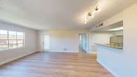 Located at 7575 Hampton Boulevard in North Lauderdale, Florida, this one-bedroom, one-bathroom unit offers a well-organized, efficiently designed single-floor layout. Light wood-style flooring runs throughout the entire space, creating a cohesive and clean aesthetic. The open living area is bathed in natural light from multiple windows with blinds, and features a textured ceiling with modern track lighting that adds a functional yet stylish touch. A partial-wall peninsula separates the living room from the kitchen, which is equipped with stainless steel appliances including a refrigerator, range, and built-in microwave. White cabinetry and granite-style countertops complete the kitchen's contemporary look, while a skylight overhead adds an additional source of natural brightness. The bedroom is a comfortable, well-proportioned room with a large window offering outdoor views and a dedicated closet for storage. The bathroom includes a full tub-shower combination with white tile surround, a granite-topped vanity, and wood-style flooring that carries through from the rest of the unit. Neutral wall tones throughout contribute to an airy, move-in-ready ambiance ideal for comfortable everyday living.