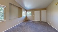 Located at 941 Danrose Dr in American Canyon, California, this single-floor, two-bedroom, two-bathroom home offers a functional and comfortable layout. The living room features vaulted ceilings, neutral beige walls, plush carpeting, and multiple windows that invite natural light and outdoor views of surrounding greenery. A built-in niche adds a distinctive architectural detail to the living area. The kitchen is well-appointed with white cabinetry, laminate countertops, white appliances including a range, refrigerator, and dishwasher, and durable wood-look flooring — all arranged in an efficient galley-style layout with a peninsula. The primary bedroom is generously sized, offering vaulted ceilings, multiple windows with outdoor views, and a closet, while the second bedroom includes a mirrored sliding-door closet and a window for natural light. Both bedrooms are finished with soft carpeting. The two full bathrooms feature a tub/shower combination, a single-sink vanity with storage cabinetry, and wood-look flooring. A connecting hallway ties the rooms together cohesively. Throughout, warm beige tones and clean white trim create a consistent, welcoming aesthetic.