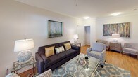 This single-floor residence offers a thoughtfully designed layout with a cohesive blend of modern and transitional finishes. The living room serves as a central gathering space, featuring crown molding, hardwood-style flooring, large windows with elegant draping, and ample room for comfortable seating. A glass-top coffee table and bold artwork contribute to the room's polished character.

The adjacent dining area accommodates a round table with seating for several guests, bathed in natural light from a generous window dressed with layered curtains and blinds. Framed artwork on the wall adds a refined touch.

The kitchen is well-equipped with dark espresso cabinetry, granite countertops, a tile backsplash, stainless steel appliances, and a curved peninsula with an undermount sink—offering both functionality and visual appeal. Hardwood-style flooring ties the space together seamlessly.

Two carpeted bedrooms provide comfortable retreats, each featuring ceiling fans, natural light, and ample space for full furniture arrangements. Both bathrooms are finished with dark vanity cabinetry, white countertops, hardwood-style flooring, and tub-shower combinations, presenting a clean and consistent aesthetic throughout the residence.