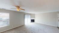 Located at 8051 Canary Ln in Indianapolis, Indiana, this single-story home offers a well-organized layout designed for comfortable everyday living. The living room serves as a central gathering space, featuring plush wall-to-wall carpeting, a ceiling fan, a textured ceiling, and a corner fireplace framed by a white surround. Large sliding glass doors fitted with vertical blinds allow generous natural light to fill the room and provide access to the exterior.

The kitchen is thoughtfully designed with white cabinetry, recessed lighting beneath a drop tile ceiling, and speckled countertops that extend into a peninsula with bar seating. The kitchen is equipped with white appliances, including a range, dishwasher, and refrigerator, and features wood-look flooring for easy maintenance. An open pass-through connects the kitchen to an adjacent dining or living area, enhancing the sense of connectivity throughout the space.

The bedrooms are carpeted and bathed in natural light through standard windows with blinds. Each room offers a neutral color palette with clean white trim. The bathrooms include wood-look flooring, speckled vanity countertops, and tub-shower combinations with white tile surrounds, providing functional and clean finishes throughout.