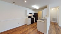 Located at 1025 Avent Hill in Raleigh, NC, this single-floor residence offers a practical and comfortable layout with a clean, neutral aesthetic throughout. The main living area is bright and welcoming, featuring warm hardwood flooring that extends through the primary living and kitchen spaces. A large multi-pane window and a door leading to a private deck invite natural light and outdoor views into the room, creating an airy atmosphere.

The kitchen is designed with functionality in mind, offering white cabinetry, a peninsula with a dual-basin sink, and black appliances including a range and refrigerator. The open pass-through design between the kitchen and living area promotes a connected, open-concept feel.

The bedroom features plush carpeting and a window that frames views of the surrounding greenery, contributing to a calm and restful environment. The textured ceiling adds a classic touch to the space. The full bathroom is efficiently appointed with a single-sink vanity featuring a light countertop, a tub-shower combination, and hardwood-style flooring.

A dedicated in-unit laundry area with a full-size washer and dryer and overhead wire shelving adds everyday convenience. Throughout the space, neutral wall tones and consistent finishes create a cohesive and move-in-ready environment.