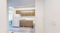 Located at 200 Folsom Street in San Francisco's vibrant SoMa district, this one-bedroom, one-bathroom unit offers a thoughtfully designed layout across a single floor. The space features a contemporary aesthetic defined by light hardwood flooring, crisp white walls, and exposed concrete ceilings that lend an industrial-modern character throughout.

The living room is a bright, open area anchored by expansive floor-to-ceiling windows that frame dynamic views of the surrounding San Francisco skyline and street activity below. Natural light floods the space, highlighting the clean lines of the room alongside a dining area tucked neatly to the side.

The bedroom continues the modern design language, featuring large windows with city and palm tree views, an exposed concrete ceiling, and warm wood flooring. A tufted black leather headboard serves as a bold focal point against the neutral palette of the room.

The bathroom is finished with light wood cabinetry, a white countertop vanity, an illuminated mirror, and light tile flooring, creating a clean and functional space.

Throughout the unit, consistent use of light wood flooring, neutral tones, and industrial concrete ceiling details tie the rooms together cohesively, making this a well-appointed urban residence in one of San Francisco's most centrally connected neighborhoods.