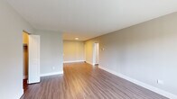 This thoughtfully designed one-bedroom, one-bathroom residence offers a comfortable and functional single-floor layout. The open living area greets you upon entry, featuring warm wood-look luxury vinyl flooring, neutral gray walls, and clean white baseboards that create a bright, cohesive aesthetic. A front-facing window allows natural light to fill the space, enhancing the airy feel of the main living area.

The kitchen is modern and well-equipped, showcasing high-gloss white upper cabinetry paired with warm wood-toned lower cabinets, white countertops, and a stylish blue subway tile backsplash. Stainless steel appliances — including a refrigerator, range, over-the-range microwave, and dishwasher — complete the kitchen's contemporary look.

The generously sized bedroom offers plush carpeting, soft neutral tones, and a window with natural light, providing a calm and restful retreat. Two closets offer ample storage throughout the unit.

The bathroom features a full tub-shower combination with striking vertically stacked gray-toned tile, white surrounding walls, and durable tile flooring, lending a clean and modern feel. The overall design of this residence balances practical functionality with contemporary style, making it a comfortable and move-in-ready space.