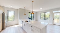 Located at 6900 W Kilgore Ave in Yorktown, Indiana, this thoughtfully designed single-floor home offers 2 bedrooms and 3 bathrooms within a well-organized, efficiently utilized layout. The interior is defined by a clean, contemporary aesthetic throughout, with light-toned luxury vinyl plank flooring, soft neutral wall tones, and crisp white trim creating a bright and cohesive feel.

The kitchen is a standout space, featuring flat-panel cabinetry in a warm wood tone alongside white lower cabinets, white quartz countertops, a subway tile backsplash, stainless steel appliances, and a single-basin sink with a matte black faucet. Gold pendant lighting adds a refined accent to the space, while black-framed windows frame scenic outdoor greenery.

The living area enjoys generous natural light through large black-framed windows and a glass door that opens to a private balcony with open rural views. The primary bedroom includes a spacious double-door closet and a ceiling fan, while the hallway connects all rooms in a clean, uninterrupted flow. Bathrooms feature wood-toned vanities, white quartz surfaces, and vertical subway tile surrounds with matte black hardware accents. A dedicated laundry room includes a full-size washer and dryer with overhead wire shelving for added storage.
