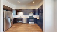 This two-bedroom, one-bathroom residence in Portsmouth, Rhode Island offers a thoughtfully designed single-floor layout with a clean, modern aesthetic throughout. Light-toned hardwood-style flooring flows seamlessly across the living spaces, complemented by crisp white walls and an open, airy feel.

The kitchen is a standout feature, outfitted with rich dark-espresso shaker cabinetry extending to the ceiling for generous storage, light countertops, stainless steel appliances including a range and dishwasher, and a window that brings in natural light. The combined dining and living area provides an open, flexible space ideal for everyday living.

Both bedrooms are well-proportioned and bright, each featuring windows with outdoor views, baseboard heating, and ample closet access — with five closets total throughout the residence. The spacious primary bedroom offers a comfortable and private retreat.

The bathroom is designed with accessibility in mind, featuring multiple grab bars, a roll-in style walk-in shower with a handheld showerhead, tile flooring, and a wide, open layout. The entrance provides a welcoming transition into the home. Overall, this residence combines functional design with modern finishes in a convenient Portsmouth location.