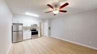 Located at 4250 E 29th St in Tucson, Arizona, this single-floor unit offers a clean, updated interior designed for comfortable everyday living. The open-concept layout seamlessly connects the living area and kitchen, both finished with light wood-style flooring that lends a bright, airy feel throughout the space. A ceiling fan with a built-in light fixture is centrally positioned, providing both airflow and ambient lighting. The textured ceiling adds a classic touch consistent throughout the unit.

The kitchen is thoughtfully appointed with white shaker-style cabinetry, granite-look countertops, a stainless steel refrigerator, electric range with oven, and a built-in sink with a modern faucet. An overhead range hood and abundant upper cabinet storage make this kitchen both functional and visually clean.

The living area is generously proportioned, featuring a wall-mounted window unit for climate control and a large window that allows natural light to filter in, with a white entry door providing direct access. The neutral gray wall tones create a versatile backdrop throughout.

Additional highlights include a walk-in closet with built-in shelving and hanging rods, offering practical storage solutions. The overall design is understated and move-in ready, making it a functional and well-equipped space in a convenient Tucson location.