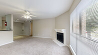 This single-floor residence offers three bedrooms, one bathroom, and a combined kitchen and living area thoughtfully arranged for everyday functionality. The living room serves as the heart of the home, featuring a classic wood-surround fireplace, plush neutral carpeting, a ceiling fan with light fixture, and a large window that invites natural light and outdoor views. The kitchen connects seamlessly to the living area via a pass-through counter, and is equipped with white cabinetry, dark granite-style countertops, a stainless steel sink, a white range, refrigerator, and a dishwasher, all set atop warm wood-look flooring. The primary bedroom is a well-proportioned retreat, offering carpet flooring, a ceiling fan, and direct access to the shared bathroom. The remaining two bedrooms are similarly carpeted and each feature ceiling fans, offering comfortable and versatile spaces. The full bathroom is clean and functional, appointed with a dark granite-style vanity, white cabinetry, a tiled shower-tub combo, and wood-look flooring. Additional spaces include a closet, a hallway, and a dedicated entrance, contributing to a practical and organized layout throughout.
