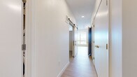 Located at 4757 Hiawatha Ave in Minneapolis, MN, this thoughtfully designed one-bedroom, one-bathroom unit offers a clean, modern aesthetic throughout its compact single-floor layout. The hallway entry sets a bright, contemporary tone with light hardwood-style flooring, crisp white walls, recessed lighting, and a stylish sliding barn door that adds a functional yet design-forward touch. The open-concept living area continues the light flooring and benefits from a large picture window that invites abundant natural light and outdoor views of the surrounding Minneapolis neighborhood. The bedroom features plush carpeting for added comfort and includes a closet with bifold doors, providing practical storage. A secondary carpeted room also offers closet access, adding flexibility to the layout. The bathroom is finished with wood-look vinyl flooring, a white vanity with modern black hardware, brushed nickel fixtures, and a full tub-shower combination with classic white tile surround. A stacked washer and dryer unit is also present within the space, adding everyday convenience. Throughout the unit, the consistent use of neutral tones, clean lines, and modern hardware creates a cohesive and inviting atmosphere well-suited for urban living in Minneapolis.