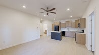 Located at 8800 Chad Colley Blvd in Fort Smith, Arkansas, this single-floor, 2-bedroom, 2-bathroom unit offers a clean, contemporary design with a thoughtful layout. The open-concept living and kitchen area is bright and airy, featuring light luxury vinyl plank flooring, recessed lighting, and a ceiling fan overhead. The modern kitchen is well-appointed with light wood-toned cabinetry, white quartz countertops, a central island with dark cabinetry, and black appliances including a refrigerator, range, microwave, and dishwasher — providing ample prep and storage space. Both bedrooms are comfortably sized, with plush carpet flooring and ceiling fans. The primary bedroom includes direct access to a dedicated walk-in closet with built-in shelving and hanging rods, as well as a second walk-in closet available for additional storage. Each bathroom features a tub-shower combination with brushed nickel fixtures, a wood-tone vanity, and white quartz countertops, maintaining a consistent, clean aesthetic throughout. The unit's neutral color palette of whites and warm wood tones creates a cohesive, move-in-ready atmosphere suited for comfortable everyday living.