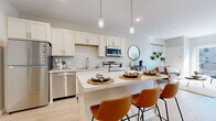 Located at 1920 Old Main St S in Cambridge, MN, this thoughtfully designed one-bedroom, one-bathroom residence offers a smart and efficient single-level layout. Light-toned luxury vinyl plank flooring runs throughout the main living areas, lending a clean, contemporary aesthetic.

The open-concept kitchen is a standout feature, showcasing crisp white shaker cabinetry extending to the ceiling, stainless steel appliances including a refrigerator, range, microwave, and dishwasher, and a central island with quartz countertops and seating for two — ideal for casual dining. Pendant lighting adds a warm, modern touch overhead.

The living room is bright and inviting, benefiting from abundant natural light streaming through a sliding glass door that opens to a private balcony with outdoor views. The bedroom is a comfortable retreat, carpeted for warmth, with a well-sized window that brings in natural light.

The full bathroom features white cabinetry, a tub-shower combination, and light wood-toned tile flooring, maintaining the home's cohesive neutral palette. A dedicated closet provides practical storage. Throughout, the space presents a clean, modern design with a warm and welcoming ambiance.