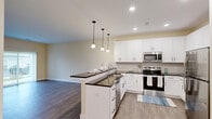 Located at 601 Flaugherty Run Rd in Coraopolis, PA, this well-appointed one-bedroom, one-bathroom residence offers a thoughtfully designed single-floor layout. The heart of the home is an open-concept living, dining, and kitchen area with wood-look flooring and warm neutral tones throughout. The kitchen is outfitted with crisp white shaker-style cabinetry, dark granite countertops, a central island with pendant lighting and an integrated sink, and a full suite of stainless steel appliances including a refrigerator, range, microwave, and dishwasher. A dedicated pantry provides additional storage. The living area is bathed in natural light from sliding glass doors that open directly onto a private patio. The bedroom features a large window with exterior views, a built-in closet, and easy access to additional storage. The bathroom offers a white vanity with dark granite countertop, a large mirror, and a tub/shower combination. Four closets throughout the unit provide generous storage capacity, while an in-unit laundry area adds everyday convenience. Wood-look flooring flows consistently across the space, contributing to a cohesive and modern aesthetic.