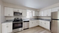 This single-floor residence offers a thoughtfully designed layout with a clean, neutral aesthetic throughout. The kitchen serves as a functional centerpiece, featuring white shaker-style cabinetry, grey marble-look countertops, and a full suite of stainless steel appliances including a gas range, over-the-range microwave, dishwasher, and refrigerator. Light wood-look flooring runs through the kitchen and main living areas, lending a bright, cohesive feel. A built-in pantry closet adjacent to the kitchen provides ample storage.

The living spaces are generously proportioned, with windows dressed in vertical blinds that allow natural light to filter in. Bedrooms are finished with plush wall-to-wall carpeting in a warm neutral tone, offering comfort underfoot. Each bedroom benefits from dedicated closet space, with at least one room featuring a walk-in closet with built-in shelving. The bathrooms are finished with light wood-look flooring, white vanities with brushed nickel hardware, and a tub-shower combination with white tile surround. Throughout the residence, the consistent use of soft white and beige tones creates a calm, move-in ready environment with a modern yet understated character.
