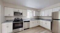 This single-floor residence offers a thoughtfully designed layout with a clean, neutral aesthetic throughout. The kitchen serves as a functional centerpiece, featuring white shaker-style cabinetry, grey marble-look countertops, and a full suite of stainless steel appliances including a gas range, over-the-range microwave, dishwasher, and refrigerator. Light wood-look flooring runs through the kitchen and main living areas, lending a bright, cohesive feel. A built-in pantry closet adjacent to the kitchen provides ample storage.

The living spaces are generously proportioned, with windows dressed in vertical blinds that allow natural light to filter in. Bedrooms are finished with plush wall-to-wall carpeting in a warm neutral tone, offering comfort underfoot. Each bedroom benefits from dedicated closet space, with at least one room featuring a walk-in closet with built-in shelving. The bathrooms are finished with light wood-look flooring, white vanities with brushed nickel hardware, and a tub-shower combination with white tile surround. Throughout the residence, the consistent use of soft white and beige tones creates a calm, move-in ready environment with a modern yet understated character.