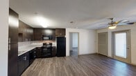 Located at 15401 Long Vista Dr in Austin, TX, this one-bedroom, one-bathroom unit offers a well-designed, single-floor layout that efficiently maximizes its living space. The open-concept kitchen and living area form the heart of the unit, featuring rich dark espresso cabinetry with modern hardware, granite-style countertops, a white subway tile backsplash, and a full suite of black appliances including a refrigerator, range, microwave, and dishwasher. Wood-look plank flooring flows consistently throughout the entire unit, adding warmth and visual continuity. The living area is bright and open, benefiting from natural light through windows fitted with blinds, and is equipped with a ceiling fan for added comfort. The generously sized primary bedroom also features a ceiling fan, wood-look flooring, and a dedicated workspace with a built-in desk. A closet with double doors and shelving provides ample storage. The bathroom includes a full soaking tub and shower combination with white tile surround, complemented by dark overhead cabinetry. A separate walk-in closet is conveniently accessible directly from the bathroom, enhancing the unit's overall functionality and storage capacity.