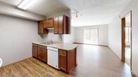 Located at 4500 E 33rd St in Sioux Falls, South Dakota, this two-bedroom, two-bathroom residence offers a well-designed single-floor layout with a comfortable and functional flow throughout. The open-concept kitchen, dining, and living area serves as the heart of the home. The kitchen is outfitted with rich cherry-toned cabinetry, light stone-patterned countertops, a peninsula with additional storage and workspace, and white appliances including a dishwasher, range, microwave, and refrigerator. Hardwood-style flooring runs through the kitchen and entryway, adding warmth and durability. The adjoining living area transitions to plush carpeting and is bathed in natural light from a large sliding glass door that opens onto a private balcony, providing pleasant outdoor views. Both bedrooms are carpeted and finished with warm wood trim, offering a cozy retreat. The spacious primary bedroom includes access to a dedicated closet with built-in shelving. Each bathroom mirrors the same design aesthetic, featuring wood vanities with stone-patterned countertops, a tub-shower combination, and neutral tile flooring. Textured ceilings are consistent throughout the space, and baseboard heating is present in key rooms, ensuring year-round comfort.