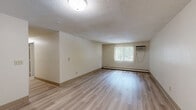 This two-bedroom, one-bathroom residence in Haverhill, MA offers a functional and well-organized single-floor layout. The unit is accessed through a welcoming entryway featuring light hardwood-style flooring, gold-tone hardware, and a chain-lock door for added security. The living room is a bright, open space with light hardwood-style flooring, a textured ceiling, baseboard heating, and a large window fitted with vertical blinds that invite natural light and views of surrounding greenery. A wall-mounted air conditioning unit provides additional climate control. Both bedrooms are carpeted in soft grey and feature textured ceilings, large windows with vertical blinds, and generous closet space with bifold doors. The primary bedroom offers ample room and connects conveniently to the main hallway. The bathroom is clean and well-appointed, featuring a full tiled tub-and-shower combination, a toilet, and a vanity with hardwood-style flooring and baseboard heating. Throughout the residence, neutral warm-beige walls and consistent finishes create a cohesive, move-in-ready atmosphere. The thoughtful layout maximizes the use of space, making this a practical and comfortable home.