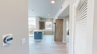 Located at 1338 W Jefferson Blvd in Los Angeles, this single-floor, three-bedroom, two-bathroom unit delivers a thoughtfully designed modern interior with a cohesive aesthetic throughout. The open-plan living room is immediately striking, featuring expansive floor-to-ceiling glass walls and sliding doors that flood the space with natural light and provide direct access to an outdoor balcony with urban views. Light-toned wood-style flooring runs continuously through the main living areas, reinforcing a clean, contemporary feel.

The kitchen is a functional and visually engaging space, anchored by a central island with bar seating and a white quartz countertop. Bold navy and white chevron tile creates a dramatic backsplash, complemented by light wood cabinetry, stainless steel appliances, and a window overlooking the streetscape. The kitchen connects seamlessly to the living area, supporting an open, social layout.

The bedrooms are compact but efficiently arranged, each featuring carpeted flooring and windows with neighborhood views. The two bathrooms are finished to a high standard, showcasing chevron-patterned floor tile, wood-toned vanities, white quartz counters, and glass-enclosed showers adorned with herringbone blue tile. A central hallway connects all rooms, maintaining a logical and accessible floor plan throughout.