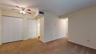 Located at 1530 Koa Dr in Springfield, Ohio, this single-floor unit presents a functional and straightforward layout across several distinct living areas. The space is finished with wall-to-wall carpeting throughout the main living and bedroom areas, contributing to a warm, understated ambiance.

The primary bedroom is notably spacious, featuring dual closets — one with louvered bifold doors and another standard panel closet — along with a ceiling fan with light fixture and a ceiling-mounted HVAC vent. An en suite area provides access to a bathroom equipped with a vanity, mirror with overhead lighting, and built-in cabinetry, as well as a separate full bathroom featuring a tiled tub/shower surround and standard fixtures.

Additional bedrooms are carpeted and receive natural light through windows fitted with vertical blinds, offering outdoor views of surrounding greenery. The kitchen includes light wood-toned laminate countertops, a double stainless steel sink, white cabinetry above and below, and under-cabinet lighting. The overall color palette throughout the unit is neutral, with cream-toned walls and white trim providing a clean, move-in-ready appearance.