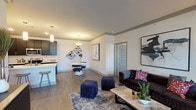 Haven on Tucker presents a well-appointed single-floor residence designed with modern living in mind. The open-concept layout seamlessly connects the living, dining, and kitchen areas, all finished with rich wood-look flooring that anchors the space. The living room is generously sized, featuring large windows dressed with elegant curtains that invite abundant natural light and offer views to the outdoors. The kitchen is a standout, boasting dark cabinetry, stainless steel appliances, a classic subway tile backsplash, and a central island with a white countertop and bar seating — ideal for casual dining or entertaining. A dedicated dining area with pendant lighting sits adjacent to the kitchen. The bedrooms are carpeted for comfort, each offering large windows with exterior views and ample room for furnishings. The primary bedroom includes access to a spacious walk-in closet with built-in wire shelving. The primary bathroom features a sleek dark vanity with a white countertop, a large mirror, and a glass-enclosed shower with marble-style tile. A secondary full bathroom includes a soaking tub with shower and matching marble-style tile. Stylish panel doors and crown molding detailing add refined architectural touches throughout.