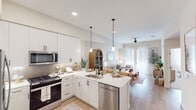 Located at 501 Avenida Vaquero in San Clemente, CA, this single-story 1-bedroom, 1-bathroom residence offers a well-designed open-concept layout filled with natural light. The combined kitchen, dining, and living area forms the heart of the home, anchored by a sleek kitchen featuring white shaker cabinetry, herringbone tile backsplash, quartz countertops, stainless steel appliances, a center island with pendant lighting, and bar seating. The living area flows seamlessly toward a glass patio door dressed in sheer drapes, allowing abundant natural light and outdoor access. A ceiling fan adds comfort throughout the shared living space. The bedroom is a calm, well-lit retreat with a ceiling fan, plush carpeting, and a large window. It connects directly to a spacious walk-in closet with built-in shelving and to the full bathroom, which features a dual-sink vanity with white cabinetry, a large mirror, and a glass-enclosed shower. The hallway includes a dedicated in-unit stacked washer and dryer closet. Light wood-style flooring runs throughout the main living areas, tying the design together with a warm, coastal-contemporary aesthetic consistent with the San Clemente setting.